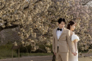 富山の中央植物園で桜と一緒にフォトウェディングを行う洋装新郎新婦