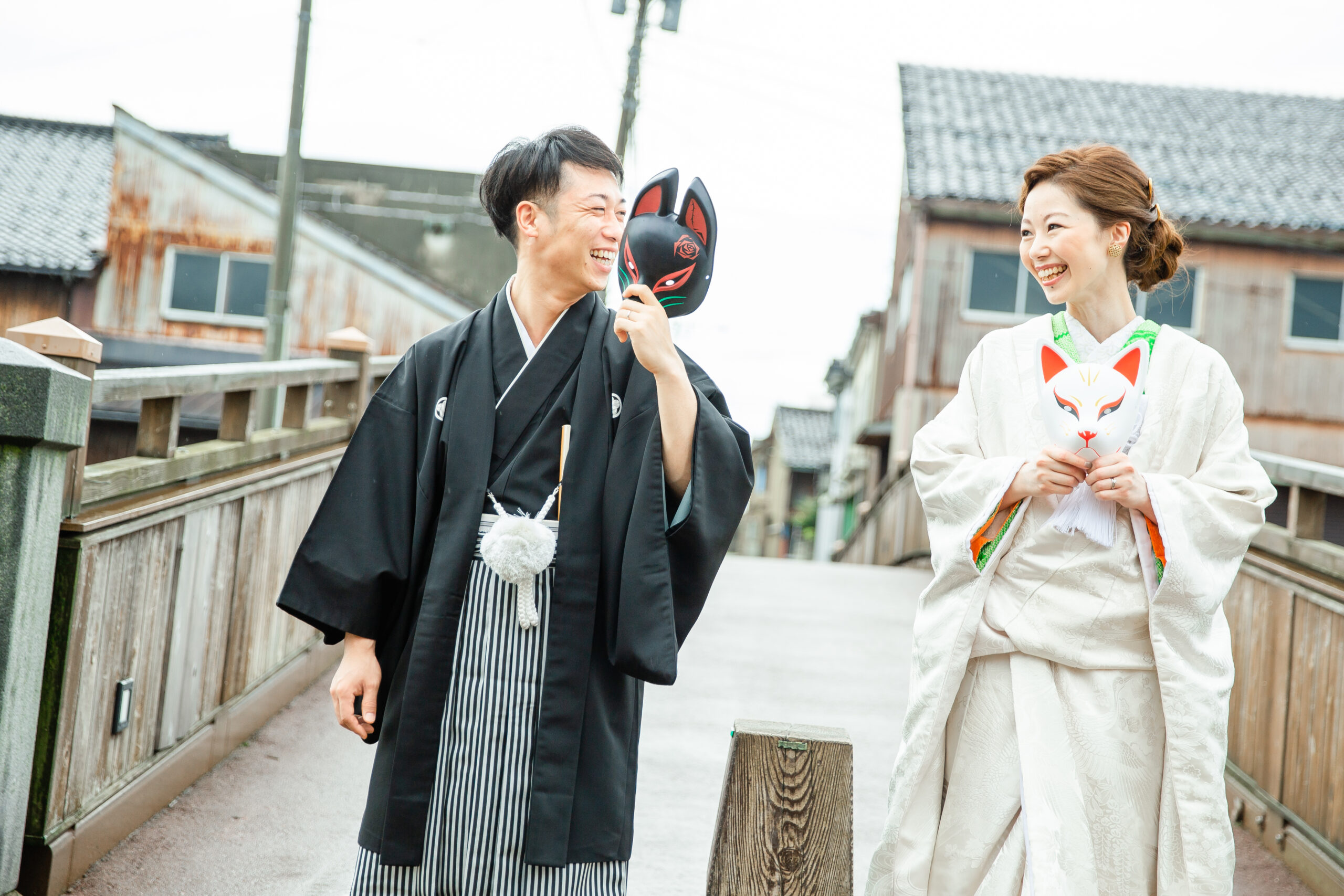 富山県射水市にあるウエディングフォトスタジオシャトンで行った新郎新婦が狐のお面を持って笑い合っているフォトウェディング