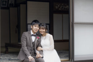 富山県射水市にあるウエディングフォトスタジオシャトンで行った新郎新婦がおばあちゃんちの縁側で頭を寄せ合い微笑んでいる様子