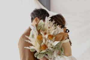 富山県射水市にあるウエディングフォトスタジオシャトンで行った新郎新婦のドライフラワーを使ったブーケで顔を隠している新郎新婦の様子
